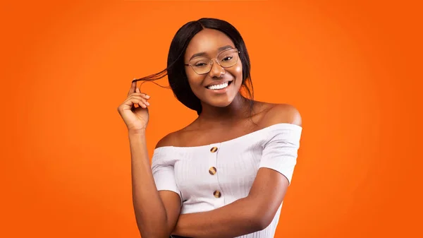 Afrikai amerikai lány játszik a haj mosolygós, narancs háttér — Stock Fotó