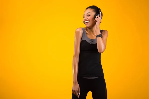 Αφρο-αμερικανική γυναίκα σε ακουστικά ακούγοντας το τραγούδι πάνω από κίτρινο φόντο — Φωτογραφία Αρχείου