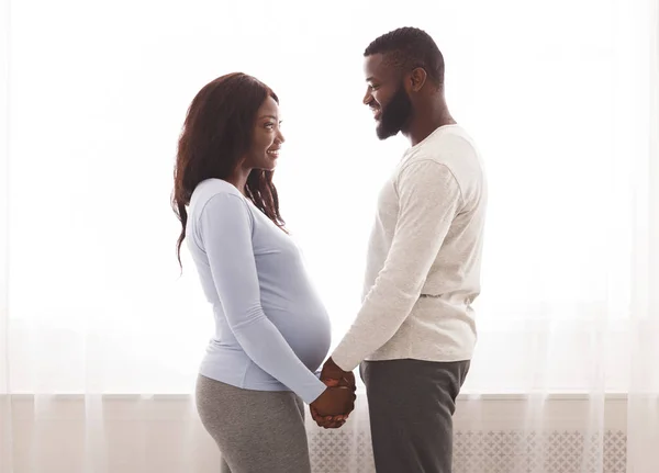 Egy terhes házaspár fogja egymás kezét és egymásra néznek. — Stock Fotó