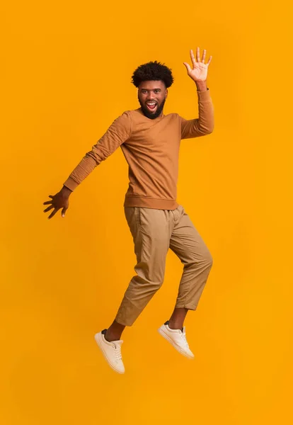 Feliz hombre negro despreocupado saltando sobre fondo naranja —  Fotos de Stock