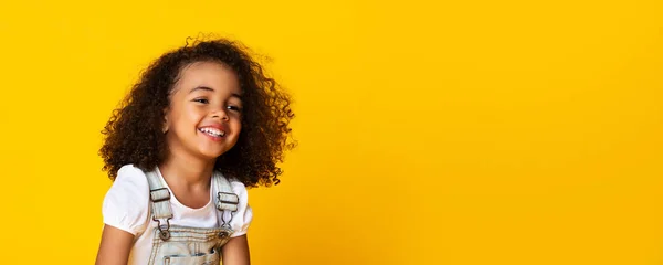 Bonito pouco preto menina sinceramente rindo sobre amarelo fundo, longo panorama — Fotografia de Stock