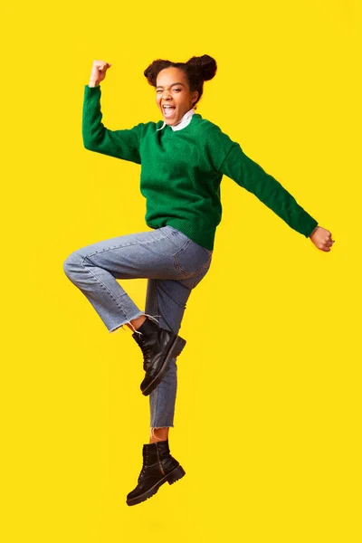 Torcendo afro teen saltando sobre amarelo fundo — Fotografia de Stock