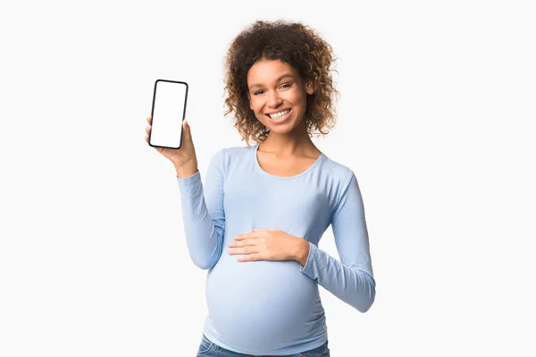 妊娠中の女性は、空白の画面で電話を示す — ストック写真