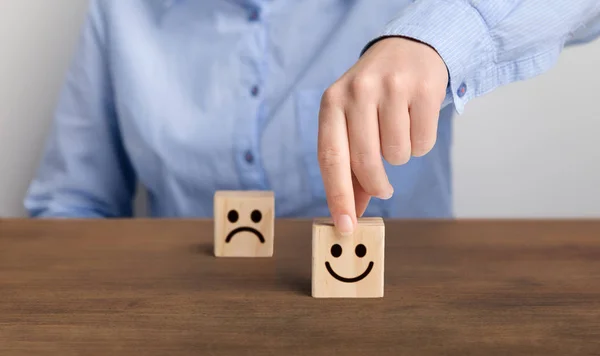 Hand van een zakenman kiest een smiley gezicht op houten blok kubus — Stockfoto