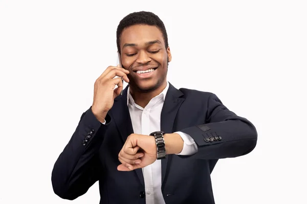 Empresario africano comprobando el tiempo hablando por teléfono — Foto de Stock