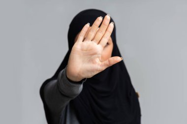 Tesettürlü Müslüman kadın elleriyle dur hareketi yapıyor.