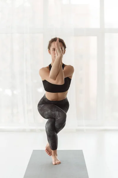 Donna che pratica l'aquila asana, bilanciamento posa yoga — Foto Stock