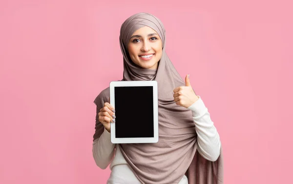 Hermosa chica árabe sosteniendo la tableta digital y el gesto pulgar hacia arriba —  Fotos de Stock
