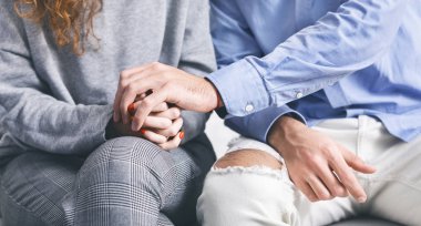 Rehabilitasyon toplantısında stresli bir kadının elini tutan adam.