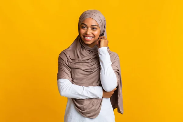 Shy black muslim girl in headscarf posing over yellow background — Stok Foto