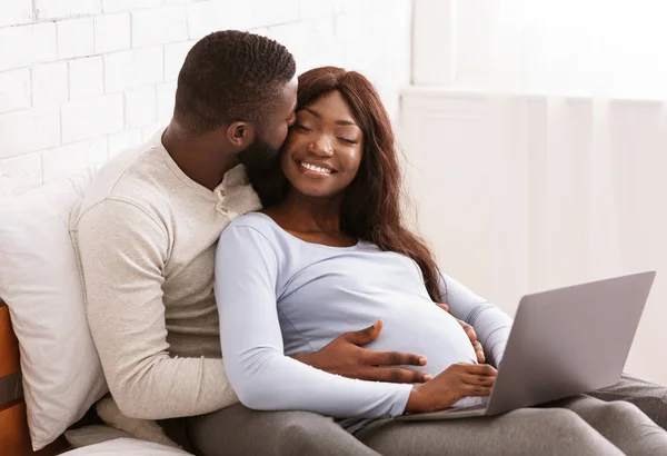 Casal grávida no amor refrigeração em casa, usando laptop — Fotografia de Stock