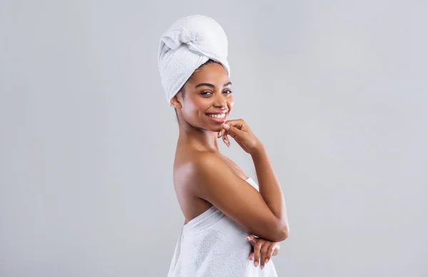 Vrolijke jonge zwarte vrouw verpakt in witte handdoeken — Stockfoto