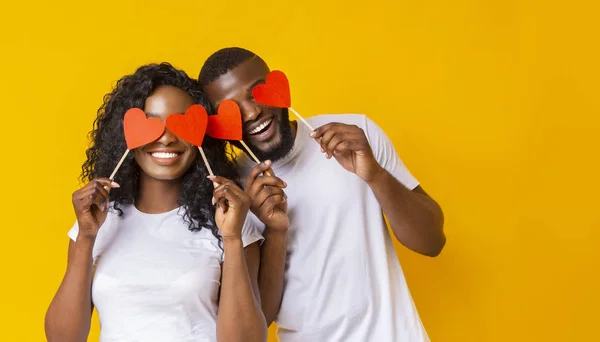 Jeune couple afro tenant des coeurs d'amour rouges sur les yeux — Photo