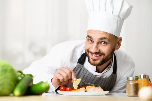 Kuchař vaření pečený losos steak plátování nádobí stojící v kuchyni — Stock fotografie