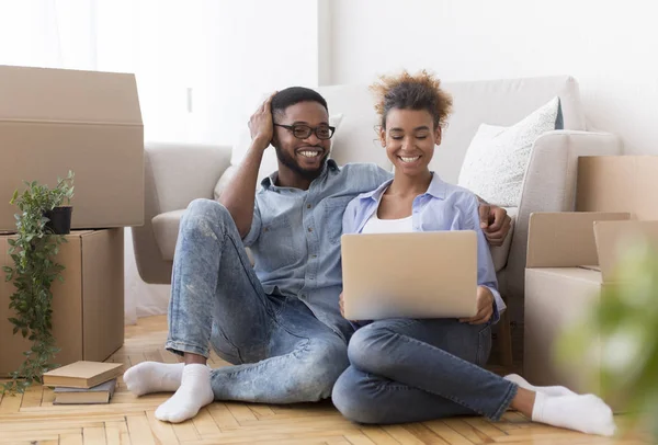 Glada par med hjälp av laptop sitter på golvet i nytt hem — Stockfoto