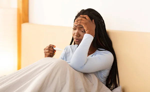 African American Lady Holding Thermometer Touching Head Sitting In Bed — Stock Photo, Image