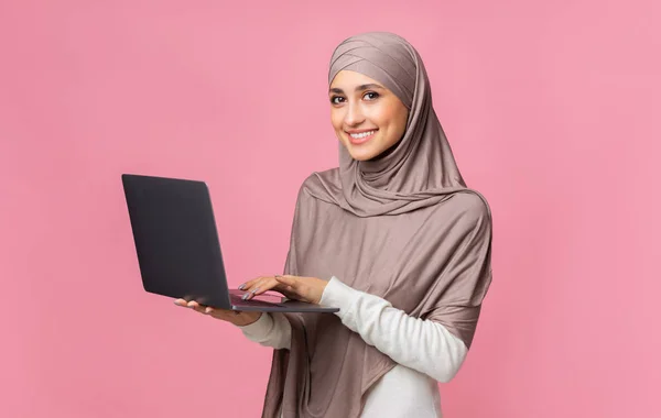 Wanita muslim tersenyum memegang laptop dan melihat ke kamera — Stok Foto