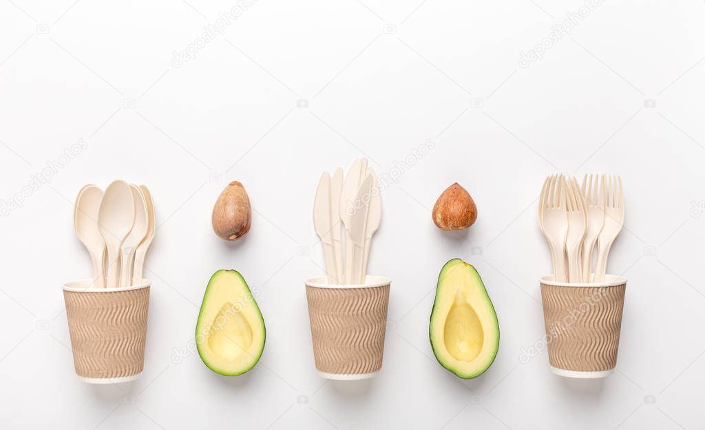 Eco plastic disposable tableware in wooden cup with avocado seeds