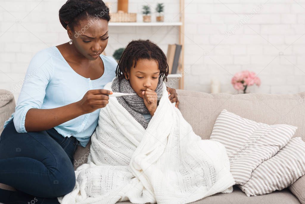 Afro mum measuring temperature of coughing kid