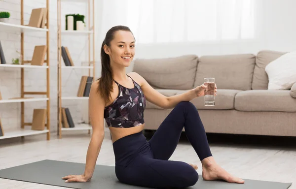 Fit vrouw rusten na thuis training en het drinken van water — Stockfoto
