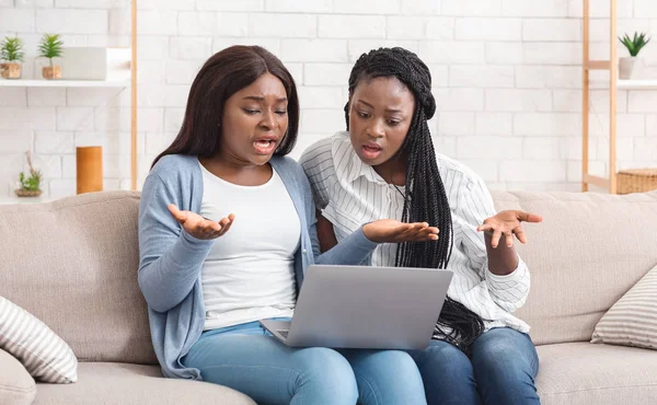 Две разочарованные черные девушки сталкиваются с проблемами с ноутбуком дома — стоковое фото