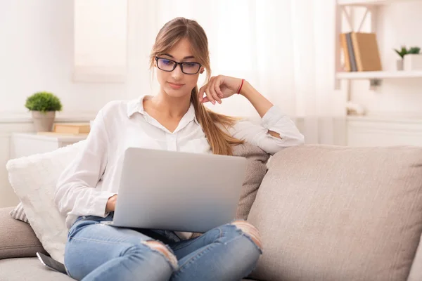 Studente ragazza utilizzando computer portatile guardando Masterclass seduto sul divano al coperto — Foto Stock