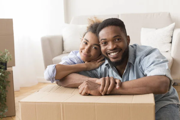 Gli sposi afro abbracciano tra scatole mobili disimballate nel nuovo appartamento — Foto Stock