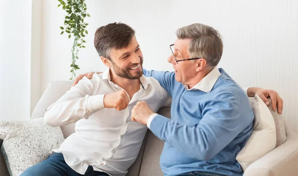 Son And Father Bumping Fists Sitting On Couch At Home — Stock Photo, Image