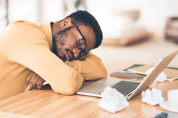 Gespannen afrikaanse amerikaanse manager liggend op bureau — Stockfoto