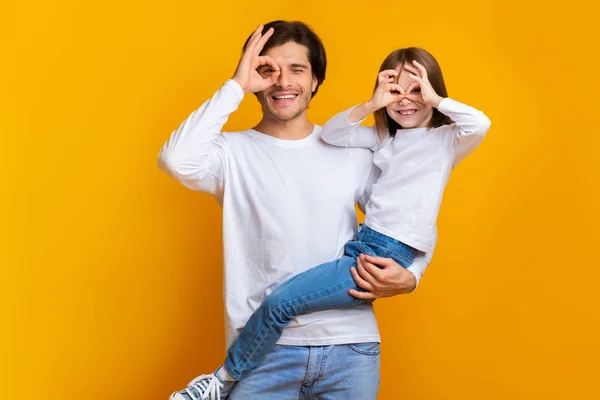 Funny girl and dad having fun on yellow background — Stock Photo, Image