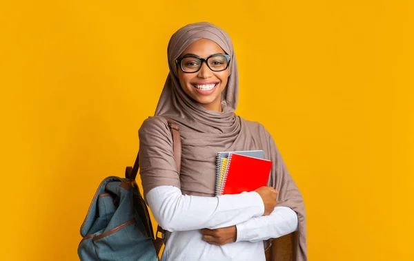 Sorrindo preto muçulmano menina no hijab com mochila e blocos de notas — Fotografia de Stock