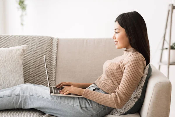 Asiática freelancer chica trabajando en línea en el ordenador portátil, vista lateral —  Fotos de Stock