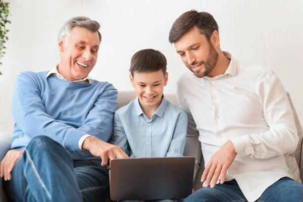 Padre y abuelo ayudando al niño a hacer la tarea sentado en el sofá —  Fotos de Stock