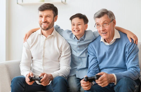 Pai alegre, avô e menino jogando videogames sentados no interior — Fotografia de Stock