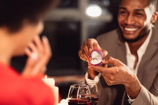 Afro uomo giving fidanzata fidanzamento anello, romantico appuntamento in ristorante — Foto Stock