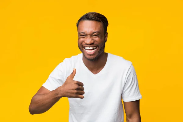 Позитивний чорний чоловік сміється і жестикулює великими пальцями вгору, студійний знімок — стокове фото