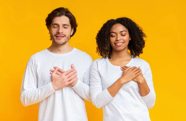 Tacksamma interracial par hålla händerna på bröstet, uttrycker tacksamhet — Stockfoto