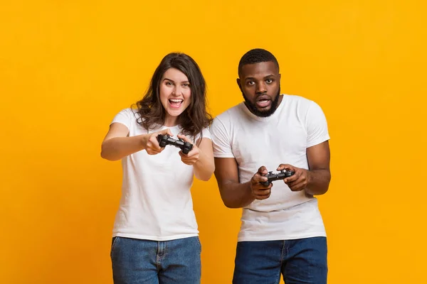 Fröhliche junge interrassische Paare spielen Videospiele mit Steuerknüppeln — Stockfoto