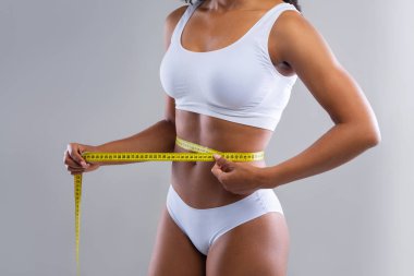 Black woman in white underwear measuring her body