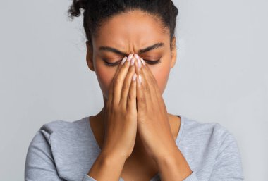 Young black woman touching her nose bridge