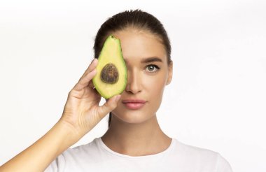 Young Lady Holding Avocado Half Near Face Posing, Studio Shot