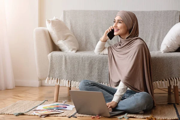 Арабская женщина в хиджабе с помощью мобильного телефона и ноутбука дома — стоковое фото