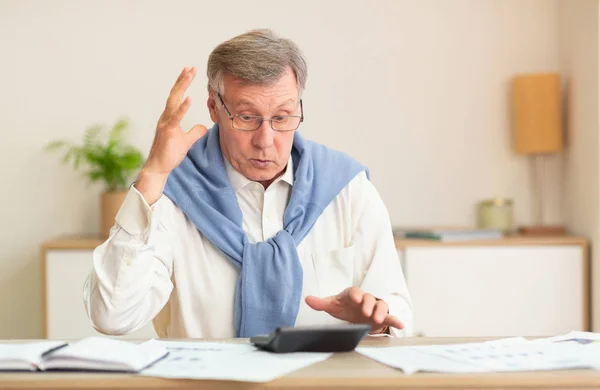 Wütender Senior berechnet Rechnungen am Schreibtisch — Stockfoto