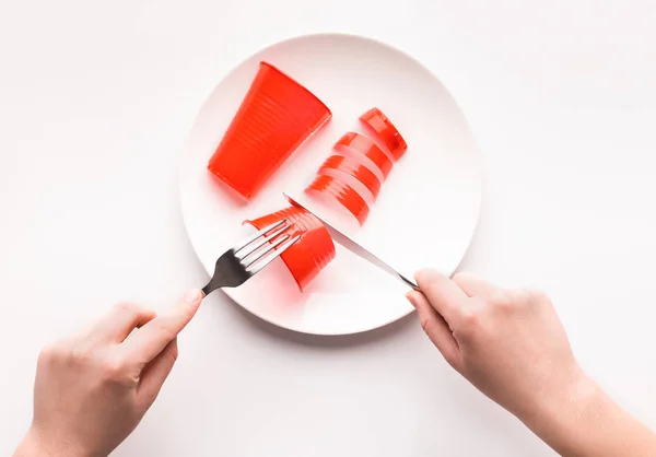 Homem comendo salsicha de plástico vermelho da placa, isolado em branco — Fotografia de Stock