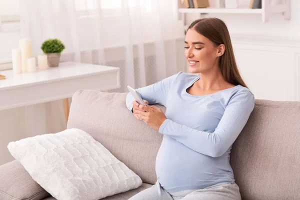 Pregnant Lady Using Phone Texting Sitting On Sofa Indoor — Stock Photo, Image