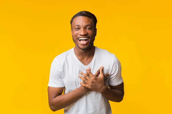 Hombre afroamericano riendo tocando el pecho parado sobre fondo amarillo —  Fotos de Stock