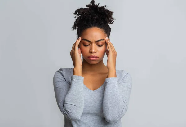 Aufgebrachte schwarze Frau mit Kopfschmerzen, die ihre Schläfen massiert — Stockfoto