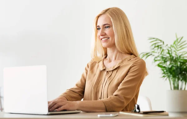 Confident middle aged woman journalist working on laptop — 스톡 사진