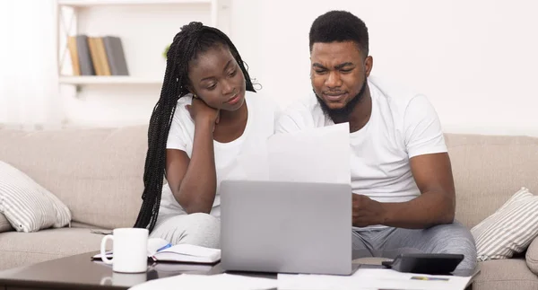 Casal preto gerenciar orçamento familiar em casa juntos, lendo documentos financeiros — Fotografia de Stock