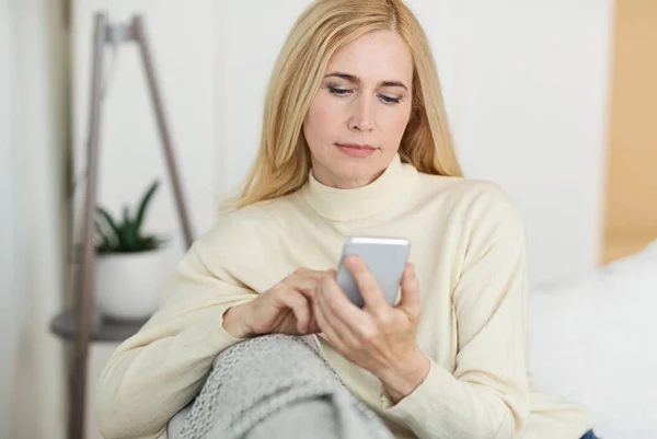 Mulher moderna surf internet no telefone, descansando no sofá — Fotografia de Stock